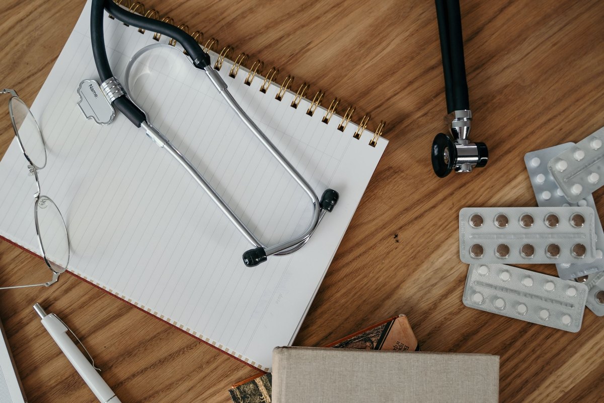 Stethoscope resting across a blank notebook on a wood desk