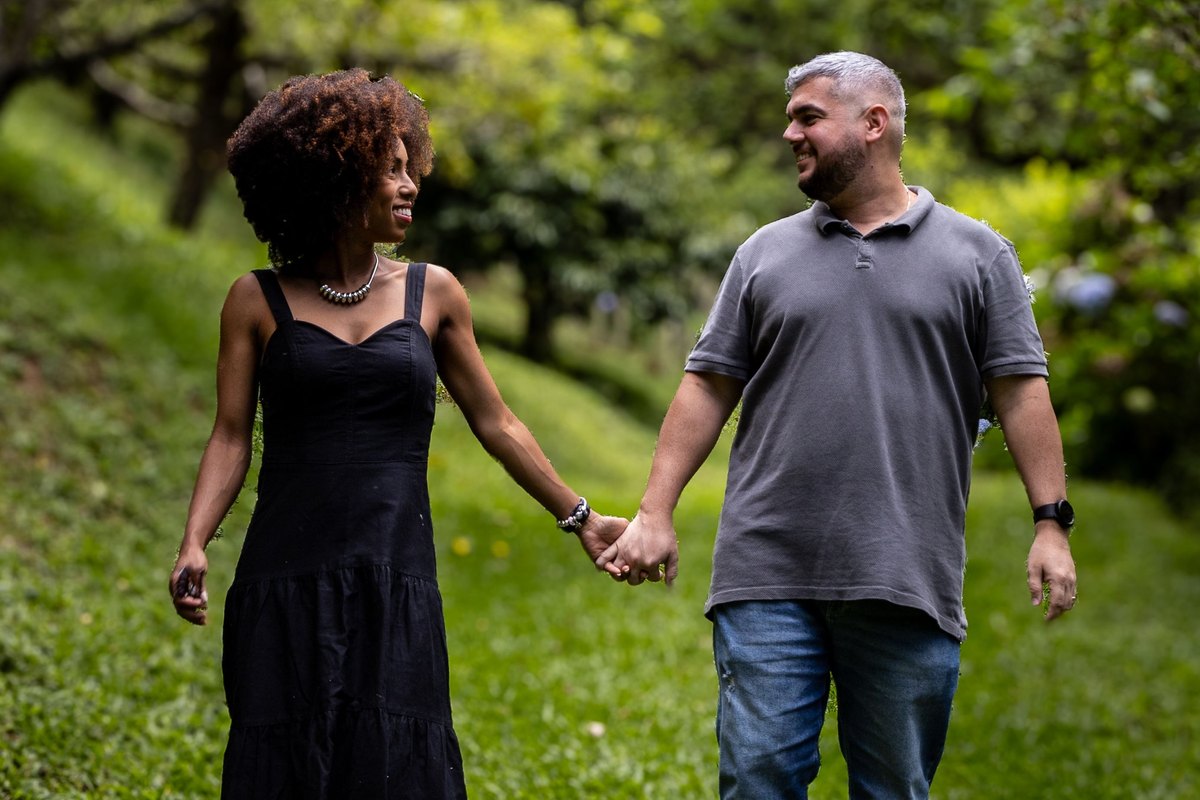 Two adults walking hand in hand beneath leafy trees