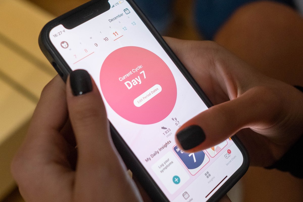 Hands checking a menstrual cycle tracker on a smartphone