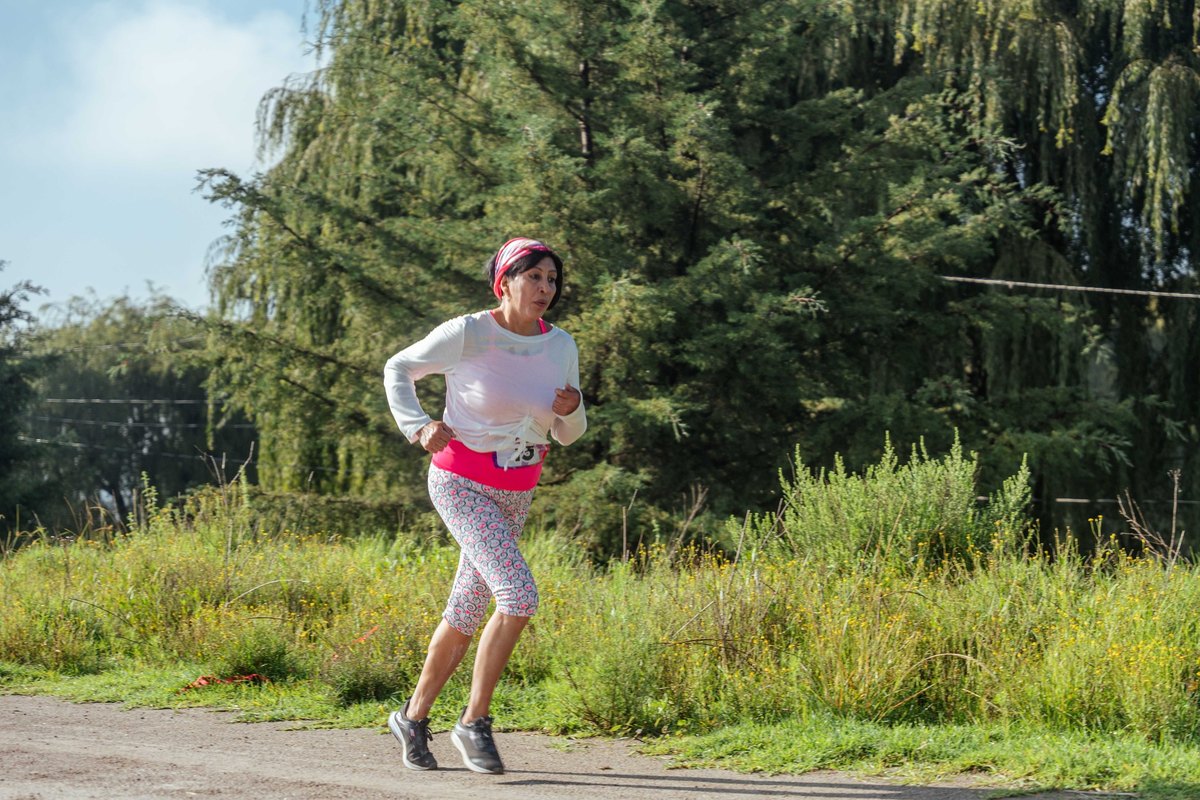 Woman in a pink headband jogging along a dirt path