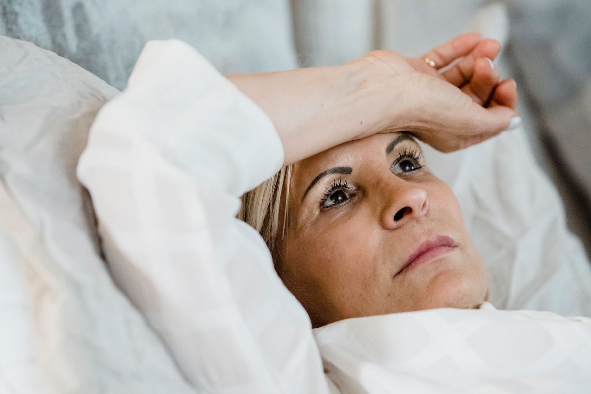 Woman resting against cushions with her hand on her forehead